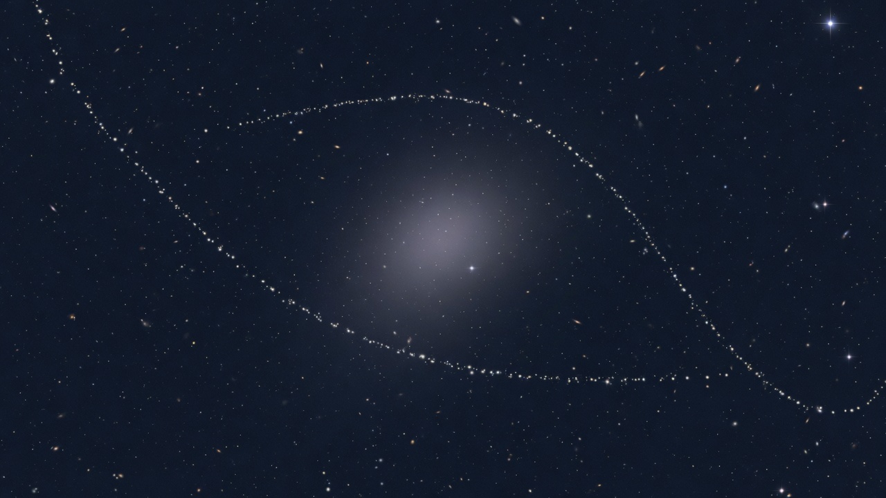 A faint ultra-diffuse galaxy with a thin ghostly ribbon of stars wrapping around it