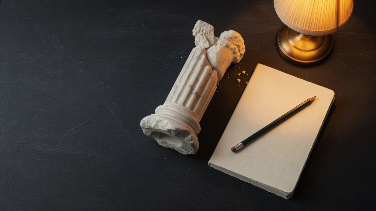 A broken marble column beside a blank notebook