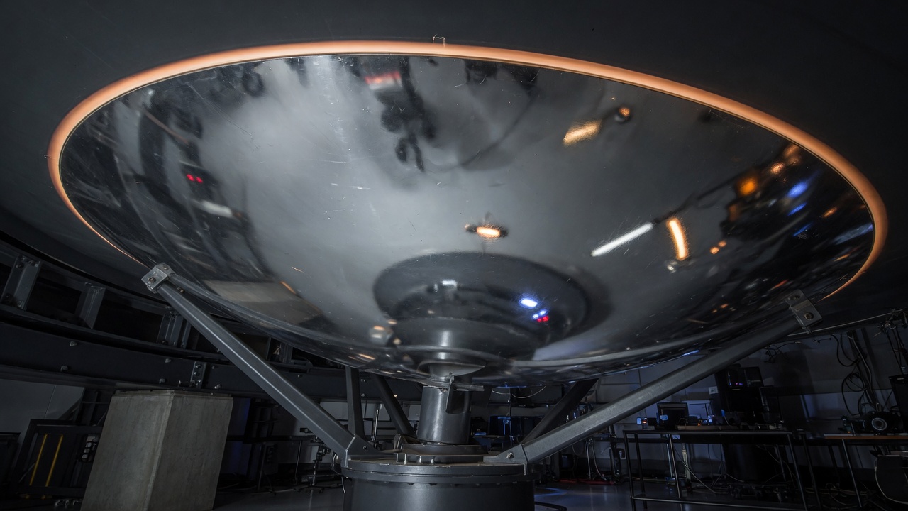 A drawing of a silver telescope mirror in a dark room