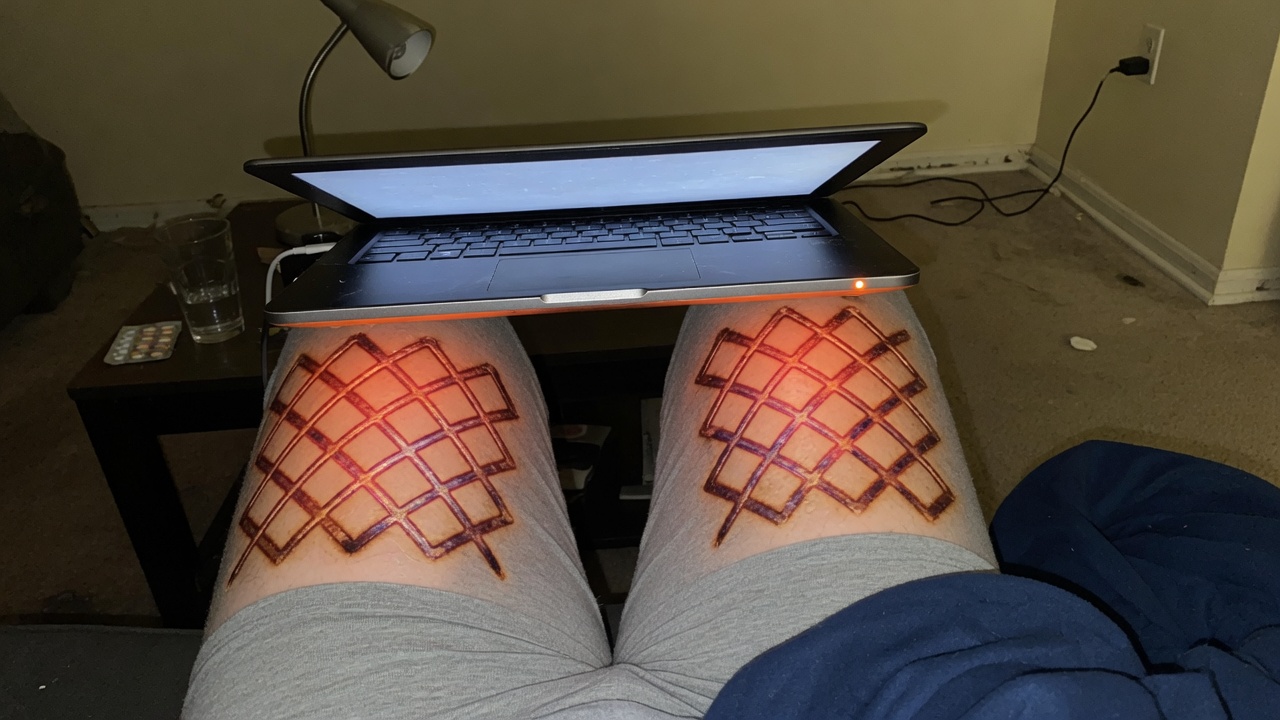 Laptop on covered thighs with a faint toasted lattice